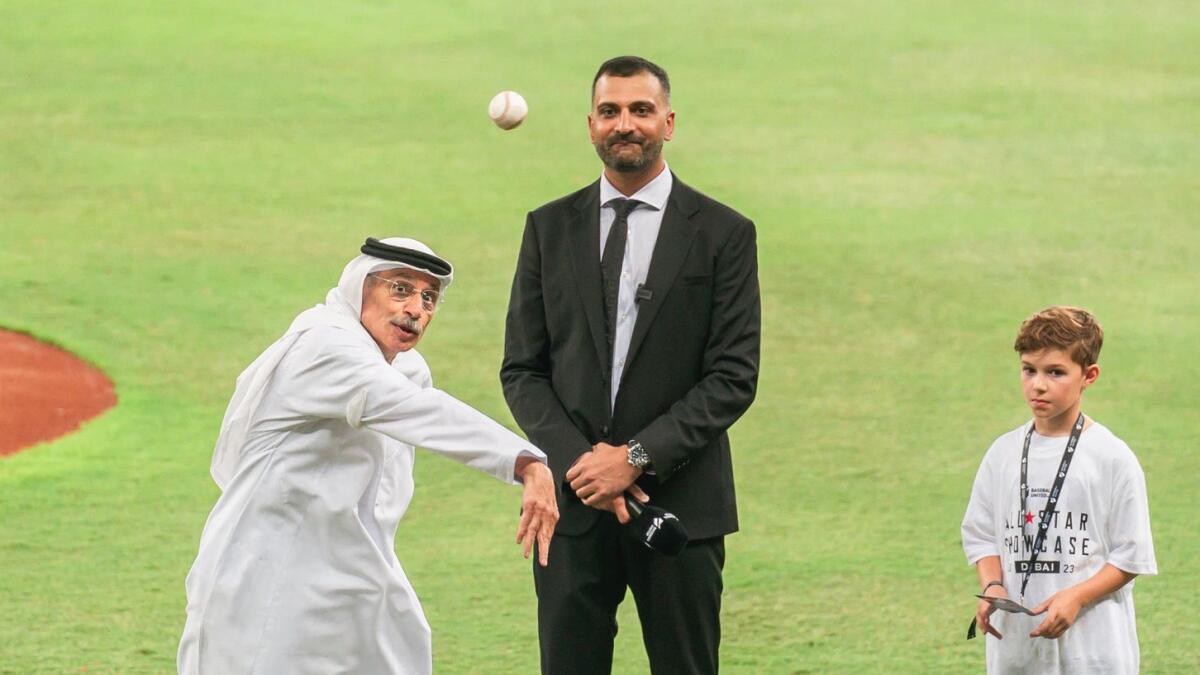 Dr. Tayeb Kamali throws the ceremonial first pitch during the first professional baseball match in Dubai,   Kash Shaikh  and a young baseball fan, look on. -Photo by Neeraj Murali.