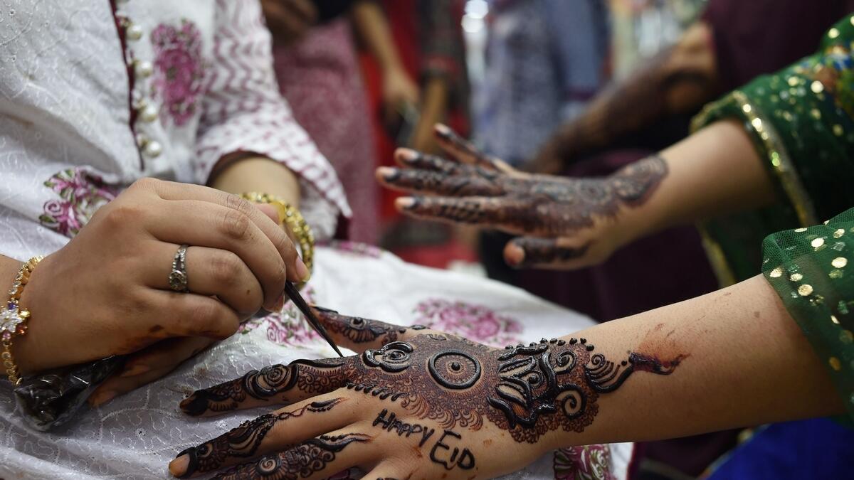 A Pakistani Muslim aesthetician applies henna on the hands of a customer, ahead of the Muslim festival of Eid Al Fitr, at a beauty parlor in Karachi.