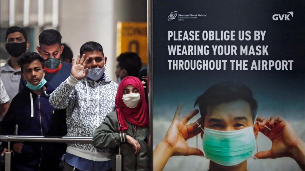 People wearing protective face masks wait for passengers to arrive at Chhatrapati Shivaji Maharaj International Airport, Mumbai, after India cancelled all flights from the UK over fears of a new strain of the coronavirus. — Reuters