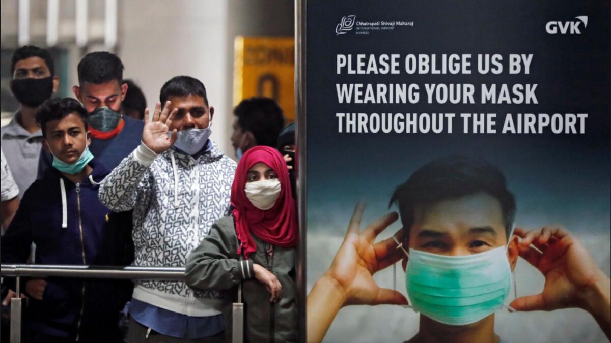 People wearing protective face masks wait for passengers to arrive at Chhatrapati Shivaji Maharaj International Airport, Mumbai, after India cancelled all flights from the UK over fears of a new strain of the coronavirus. — Reuters