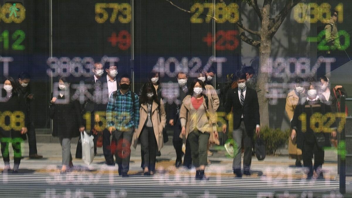 Pedestrians are reflected in a quotation board of the Tokyo Stock Exchange in Tokyo on Wednesday. Tokyo stocks opened higher  as investors cautiously welcomed tentative signs of an improvement in the COVID-19 coronavirus crisis battering the global economy. -  AFP