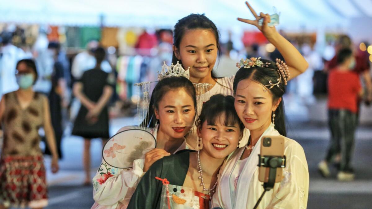 Women wearing traditional clothing posing for photos as they visit a night market in Wuhan in China's central Hubei province. Photo: AFP