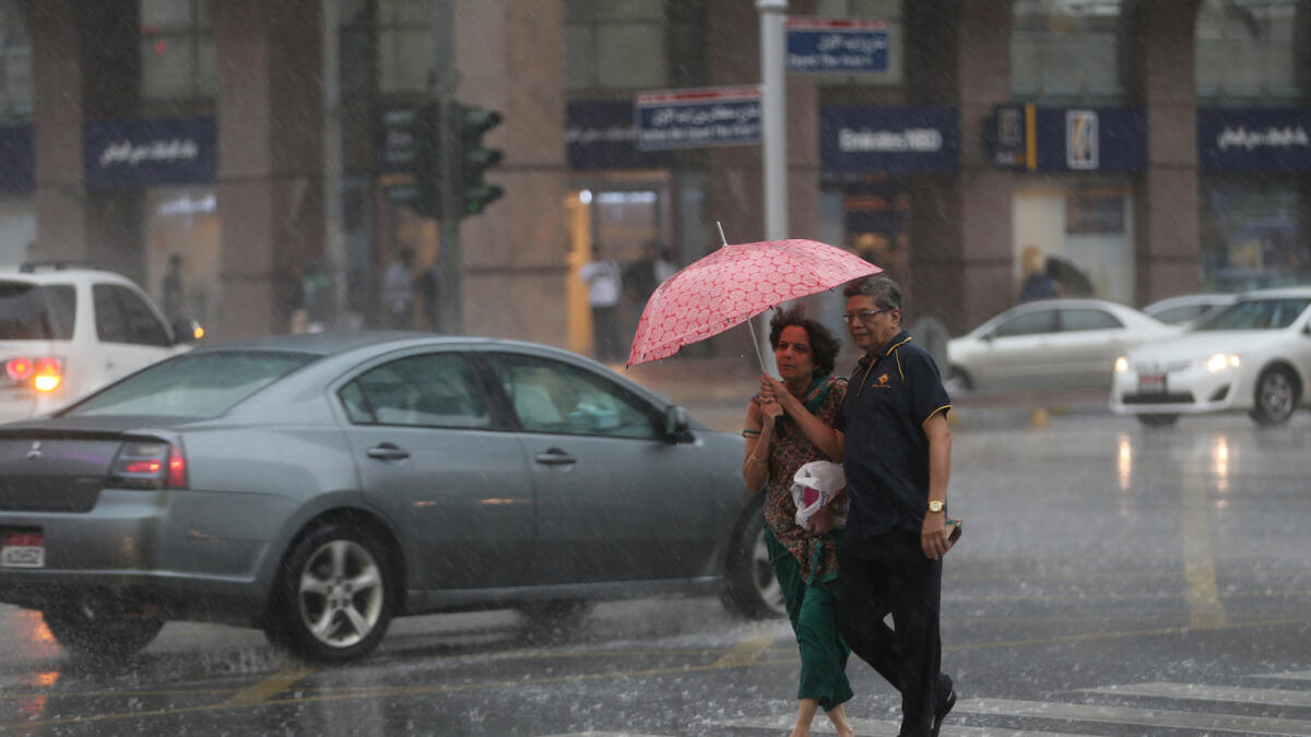Commuters cross the street on a rainy afternoon in Abu Dhabi. Photo By Ryan Lim