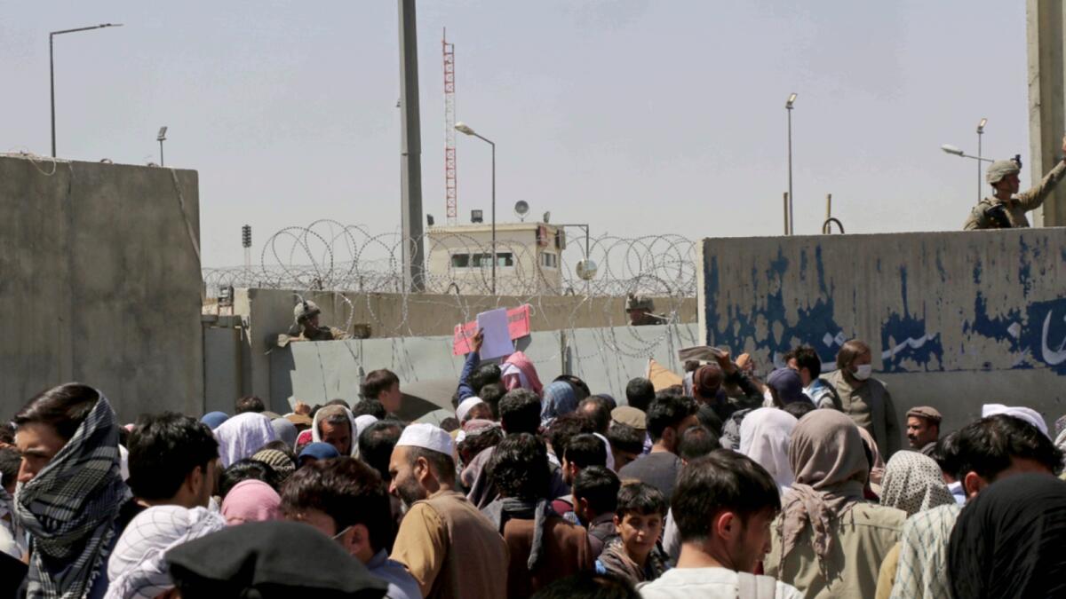 US soldiers stand inside the airport wall as hundreds of people gather near an evacuation control checkpoint on the perimeter of Kabul airport. — AP