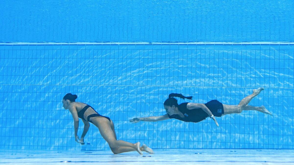 Coach Andrea Fuentes swims to rescue Anita Alvarez (left) from the bottom of the pool at the World Aquatics Championships. (AFP)