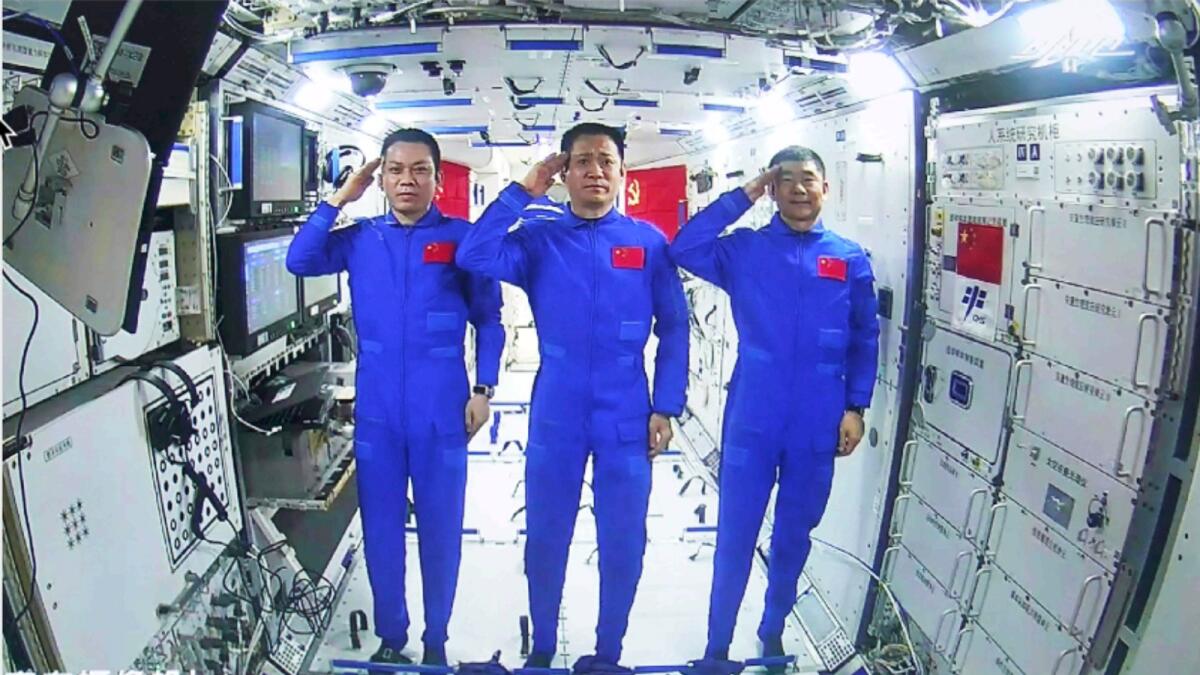 Chinese astronauts, Tang Hongbo, Nie Haisheng, and Liu Boming salute from aboard the space station Tianhe during a video conversation with  President Xi Jinping. Photo: AP