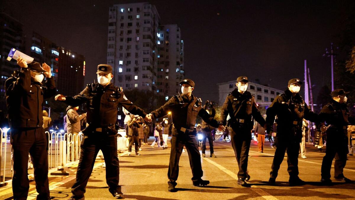 Police officers stand guard as people protest Covid restrictions and hold a vigil to commemorate the victims of a fire in Urumqi, in Beijing. — Reuters