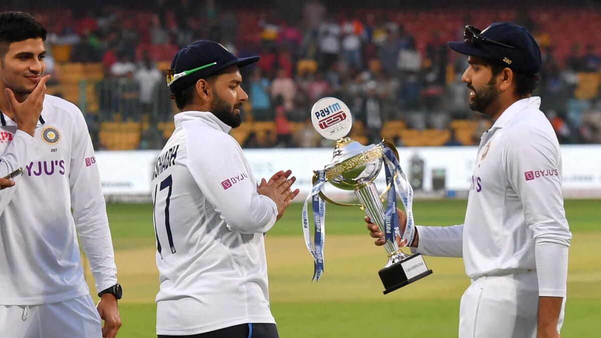India's captain Rohit Sharma (right) holds the trophy as his teammates Rishabh Pant (centre) and Shubman Gill look on after winning the Test series against Sri Lanka.(AFP)