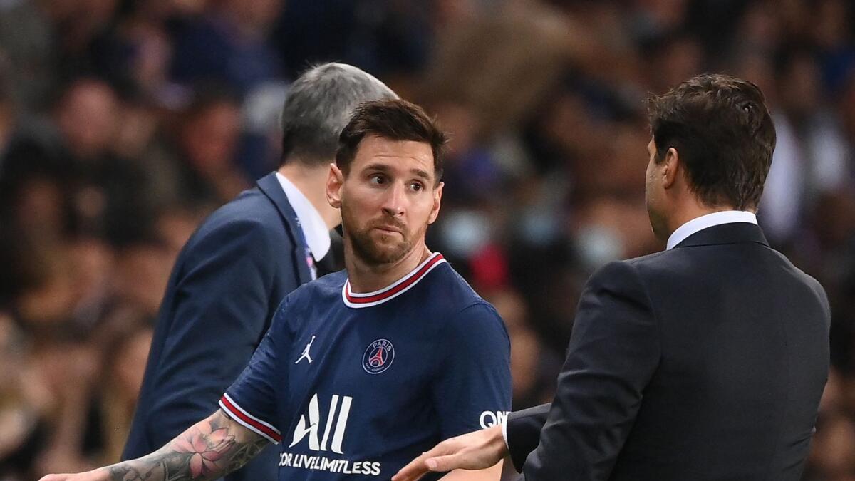 PSG's Argentinian forward Lionel Messi (left) looks at head coach Mauricio Pochettino as he leaves the pitch after being substituted during the match against Olympique Lyonnais. (AFP)