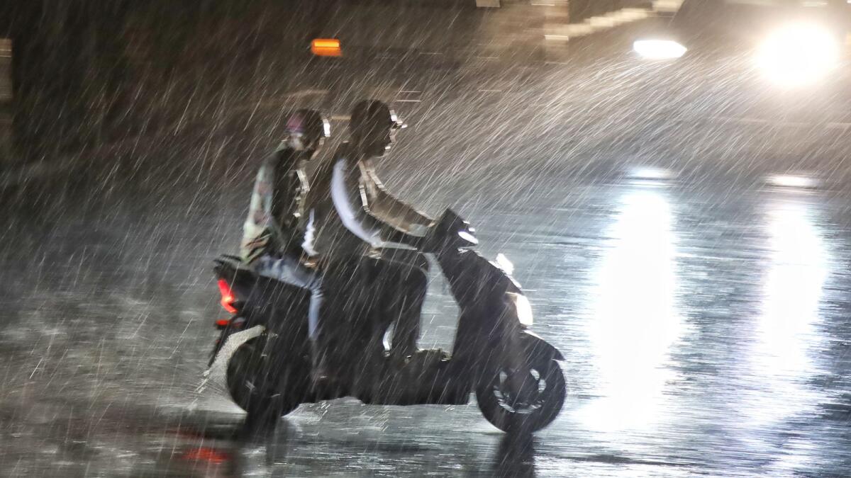 People ride a scooter on Outer Ring Road during rain in Bengaluru on April 3, 2023. — PTI