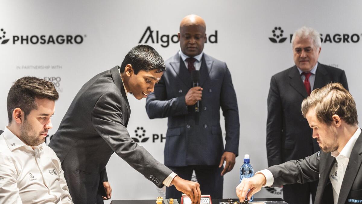 Indian prodigy Rameshbabu Praggnanandhaa (second from left) makes the ceremonialopening move during the World Chess Championship match between world champion Magnus Carlsen (right) and Ian Nepomniachtchi, in Dubai last year. — FIDE