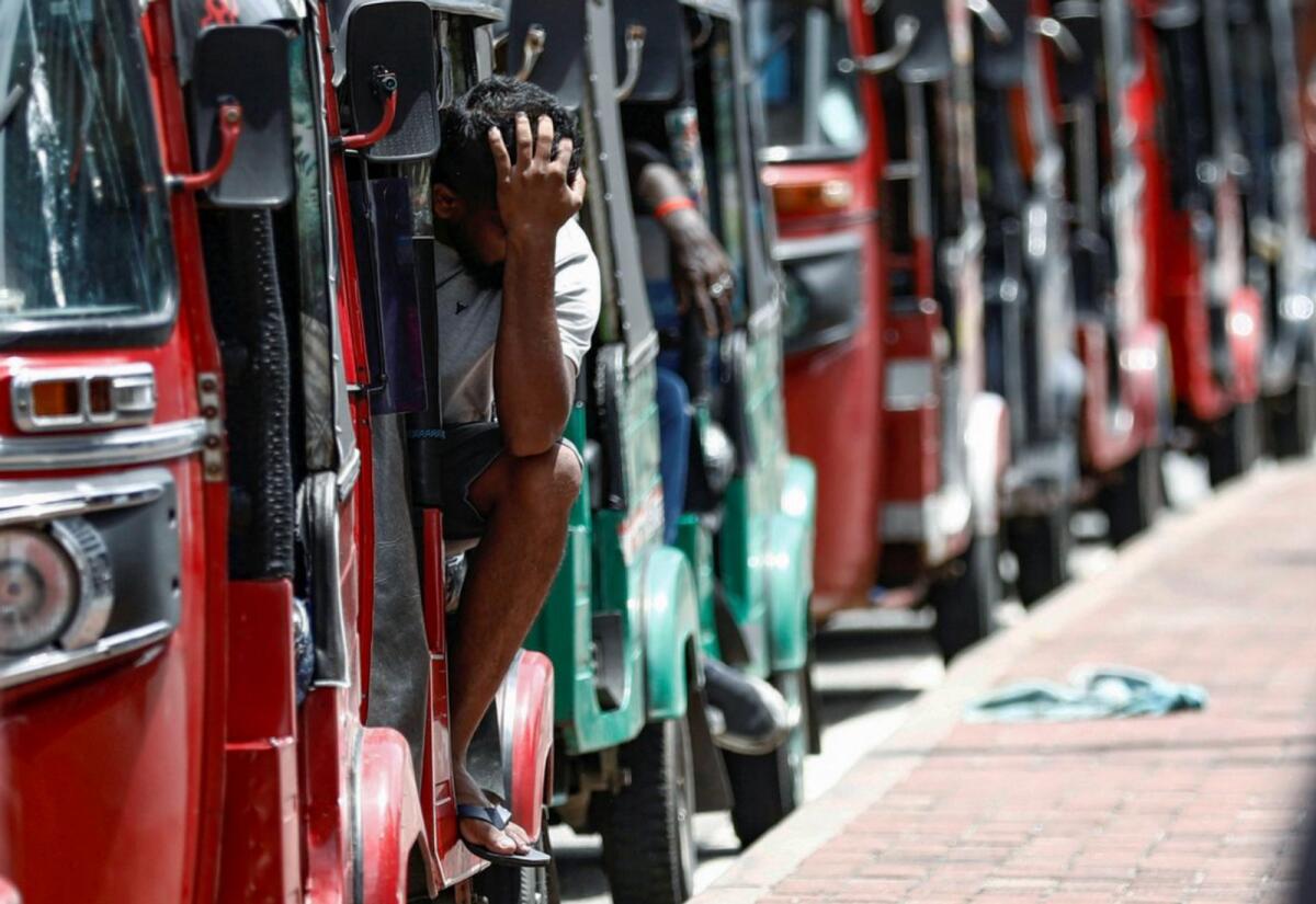 A man waits inside a three-wheeler near a line to buy petrol from a fuel station in Colombo, Sri Lanka/ REUTERS