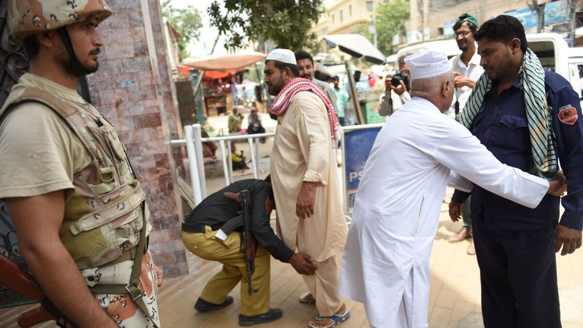 Pakistani security personnel search worshipers before entering a mosque to offer prayers ahead of the Muslim festival of Eid Al Fitr, at a mosque in Karachi on June 23, 2017.
