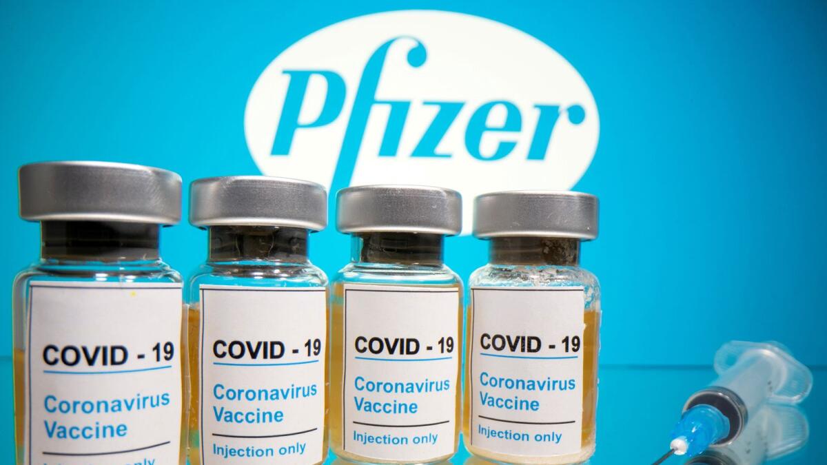 FILE PHOTO: Vials with a sticker reading, 'COVID-19 / Coronavirus vaccine / Injection only' and a medical syringe are seen in front of a displayed Pfizer logo in this illustration taken October 31, 2020. REUTERS/Dado Ruvic/File Photo
