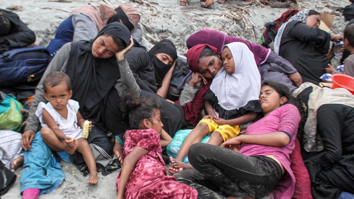 Rohingya women and children rest on the sands after they landed in Lampanah beach, Aceh province, Indonesia, on Thursday. — Reuters.