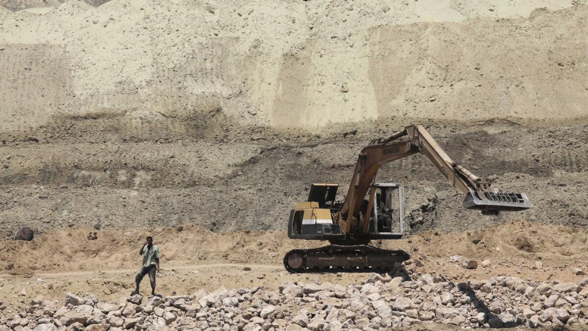 A labourer stands as a bulldozer works on a new section of the Suez Canal in Ismailia.