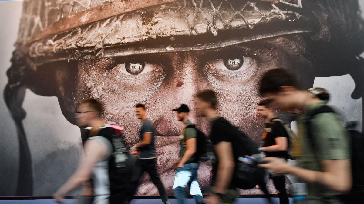 Visitors passing an advertisement for the video game 'Call of Duty' at the Gamescom fair for computer games in Cologne, Germany. British regulators have blocked Microsoft's $69 billion deal to buy videogame maker Activision Blizzard over worries that it would stifle competition in the cloud gaming market. - AP
