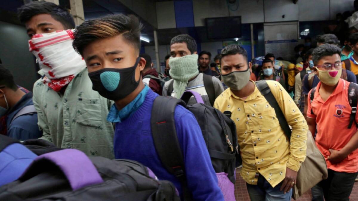 People wearing face masks as a precaution against the coronavirus arrive at a train station in Bengaluru. —AP