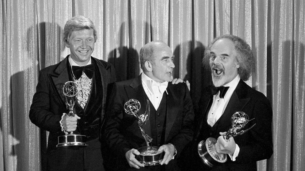 Writer William Blinn, actor Ed Asner, center, and director David Greene pose with their Emmy statuettes in Los Angeles, 1977.
