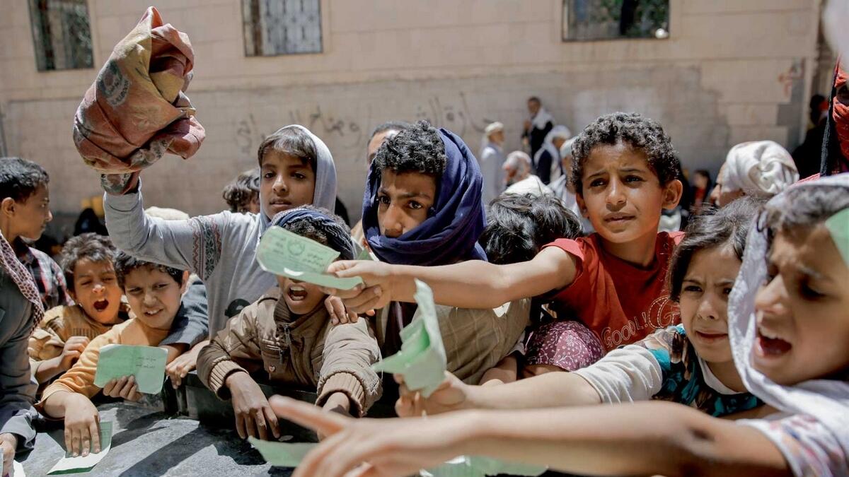 Yemeni children present documents to collect food rations provided by a local charity. — AP file
