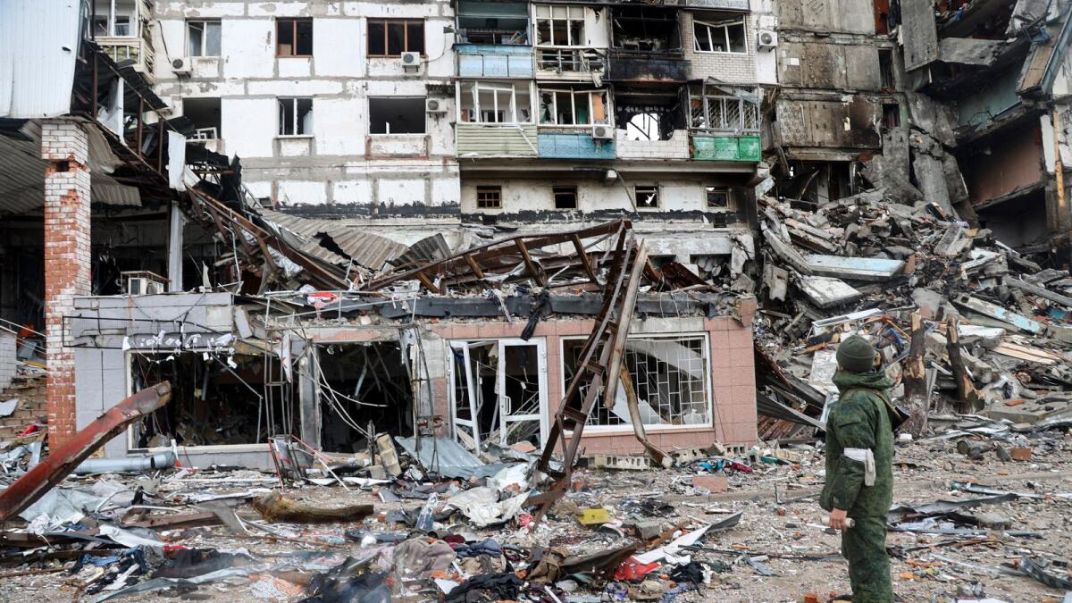 A serviceman stands at a building damaged during fighting in Mariupol. – AP