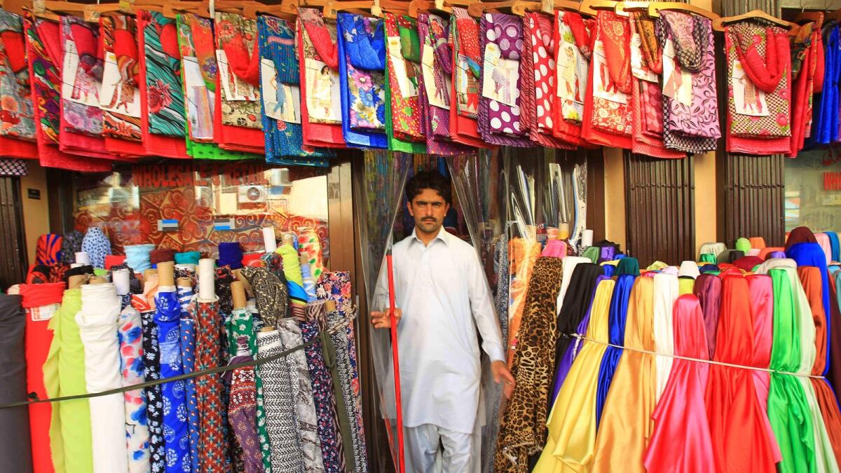 A shopkeeper stands outside a textile shop near Baniyas Square in Dubai.-Photo by Neeraj Murali/ Khaleej Times
