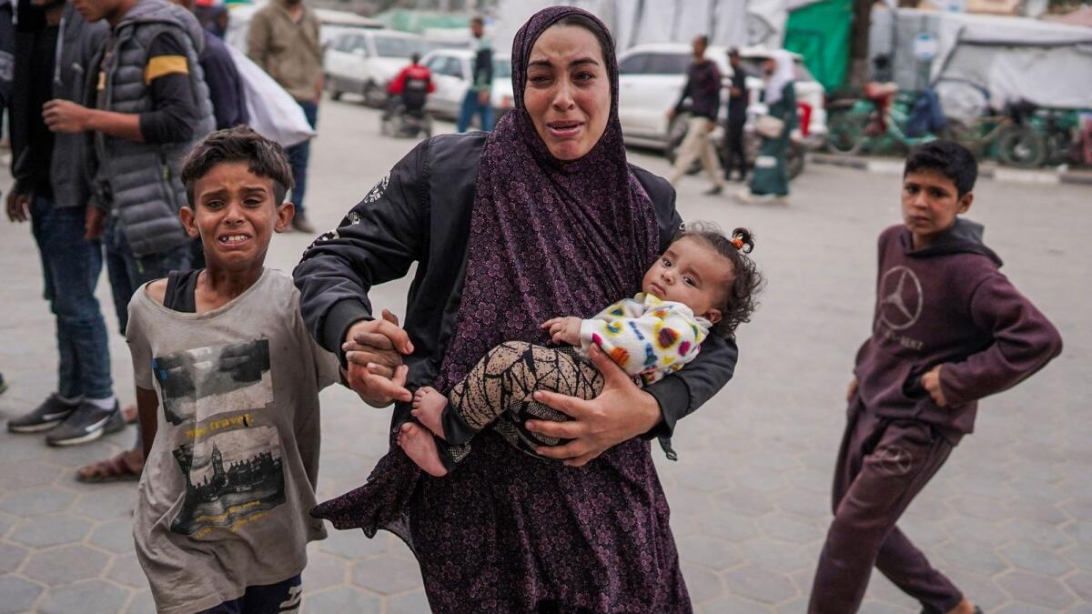 A Palestinian woman holding her children outside a hospital where casualties are brought following Israeli bombardment in Bureij, central Gaza Strip, on April 8. — Photo: AFP