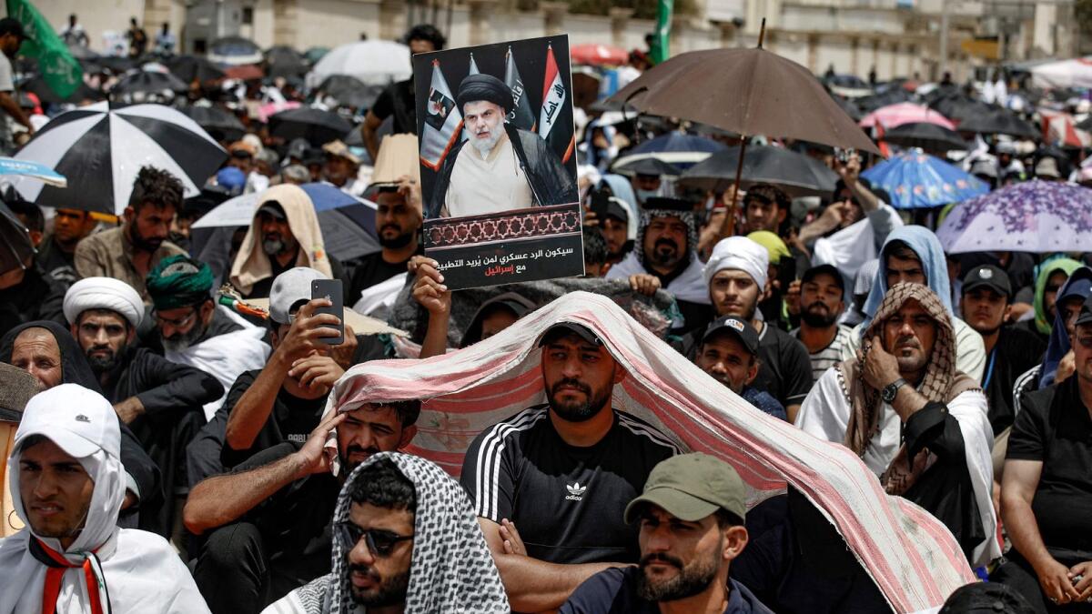 A supporters of Iraqi Shia cleric Muqtada Sadr carry his portrait following Friday prayers outside the parliament building in the Green Zone of the capital Baghdad. — AFP