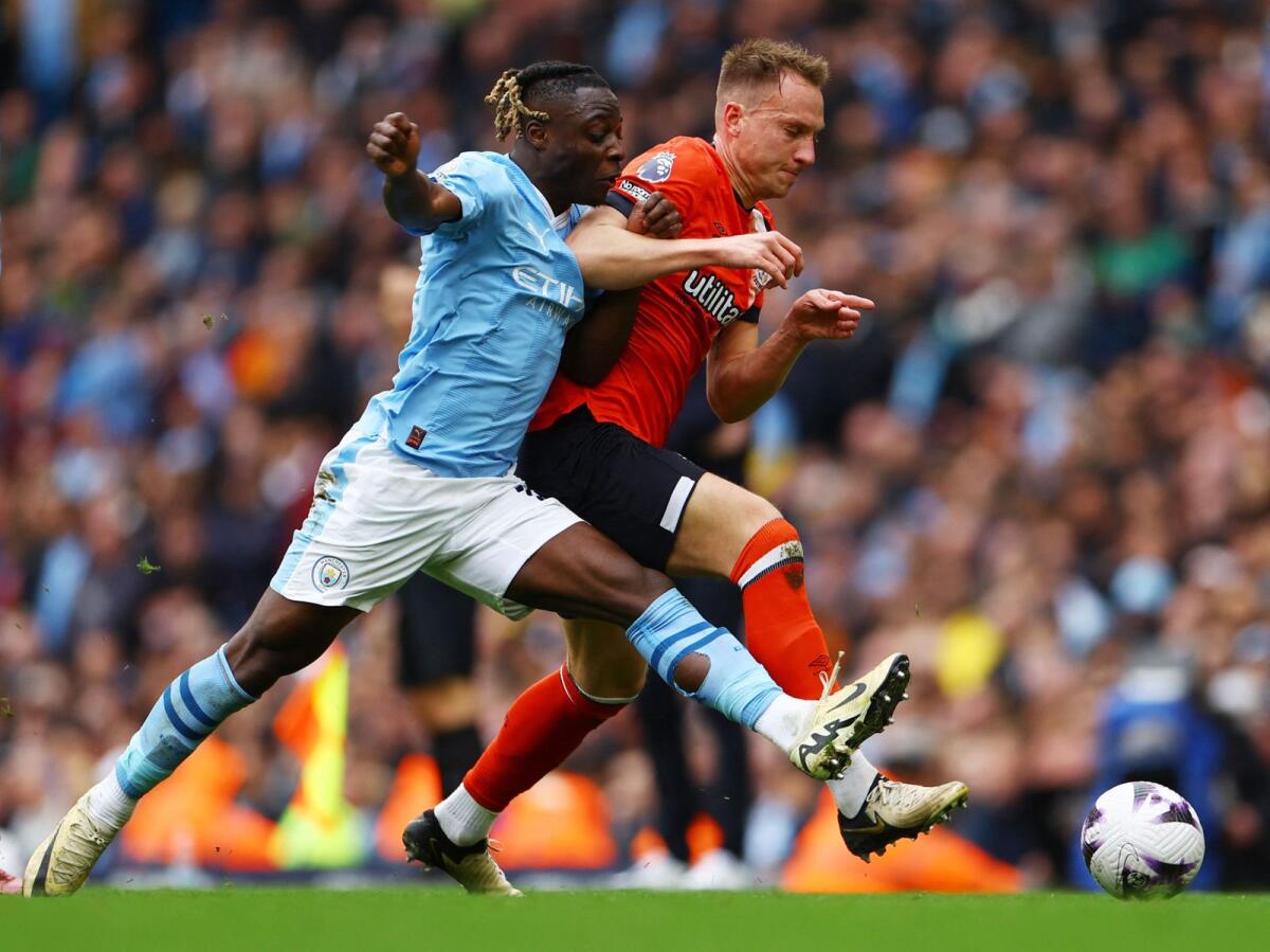 Manchester City's Jeremy Doku in action with Luton Town's Cauley Woodrow. - Reuters