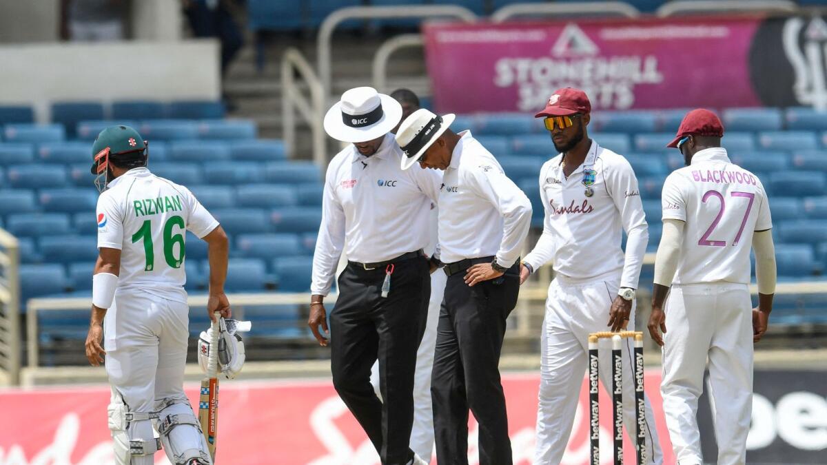 Match officials (left) are concerned about the bowler's slippery run up area as Kraigg Brathwaite (second right) of West Indies comes to ask during day 3 of the 2nd Test. — AFP)