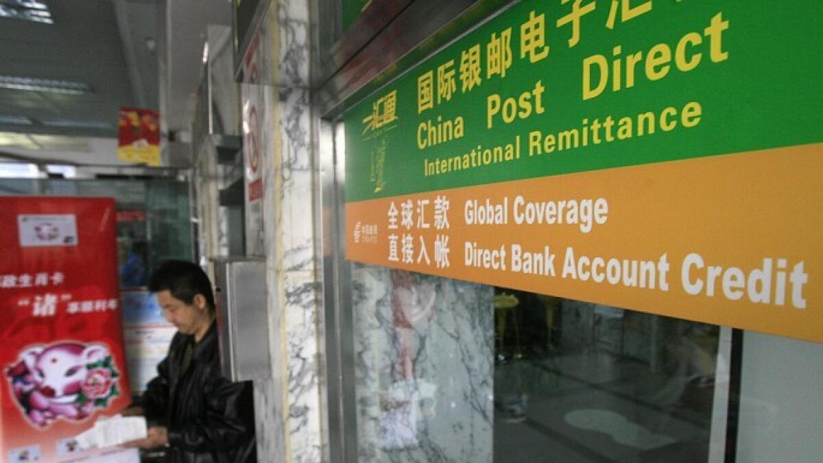 A man emerges from a post office where a Postal Savings Bank of China branch offers remittance service. 