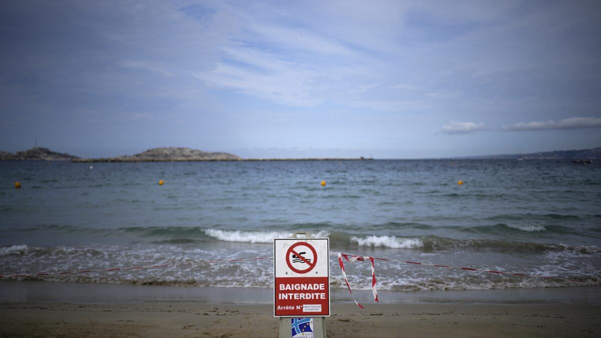 A sign reading 'swimming prohibited' sits on a beach with high levels of pollution after a storm passed through Marseille, southern France, on Thursday. — AP