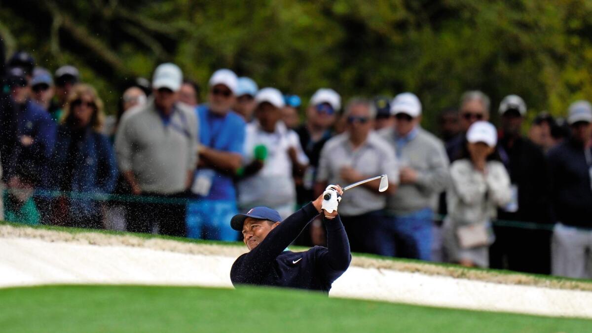 Tiger Woods hits out of a bunker on the first hole during the second round of the Masters on Friday. — AP
