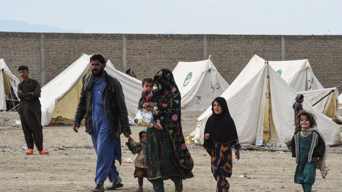 Afghan refugees walk near tents at a temporary camp as they wait to cross the Pakistan-Afghanistan border in Chaman on Wednesday. — AFP
