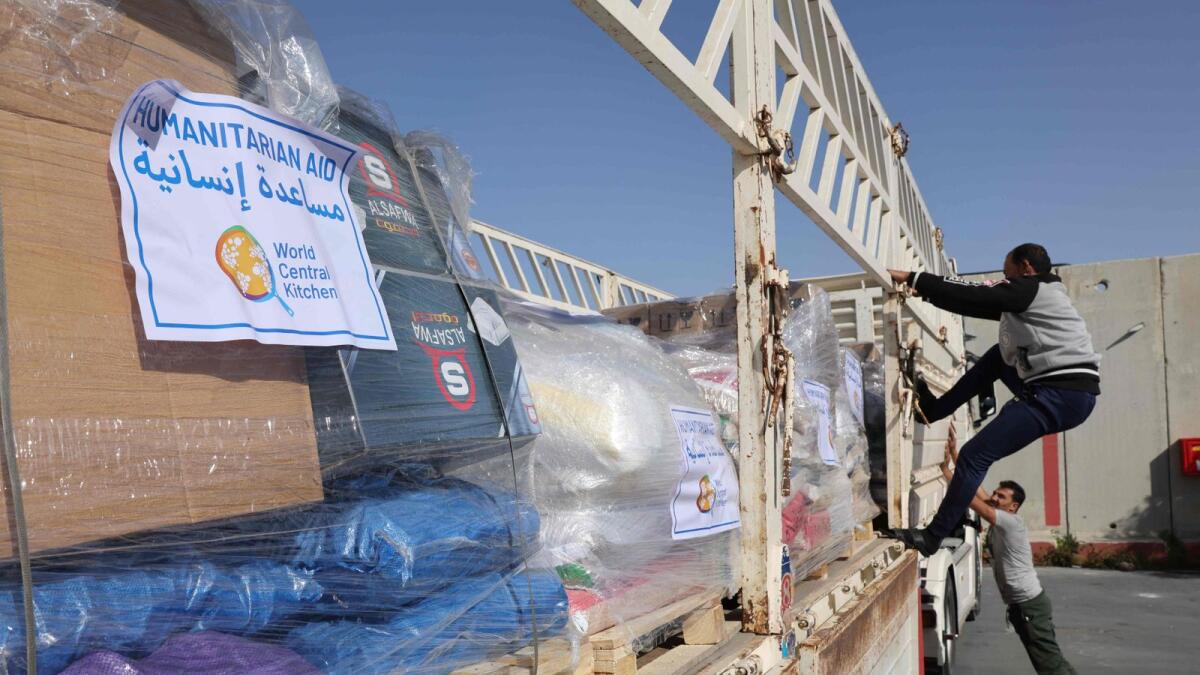 Truck drivers refasten a humanitarian aid cargo after inspection by Israeli security upon arriving from Egypt on the Israeli side of the Kerem Shalom border crossing. — AFP