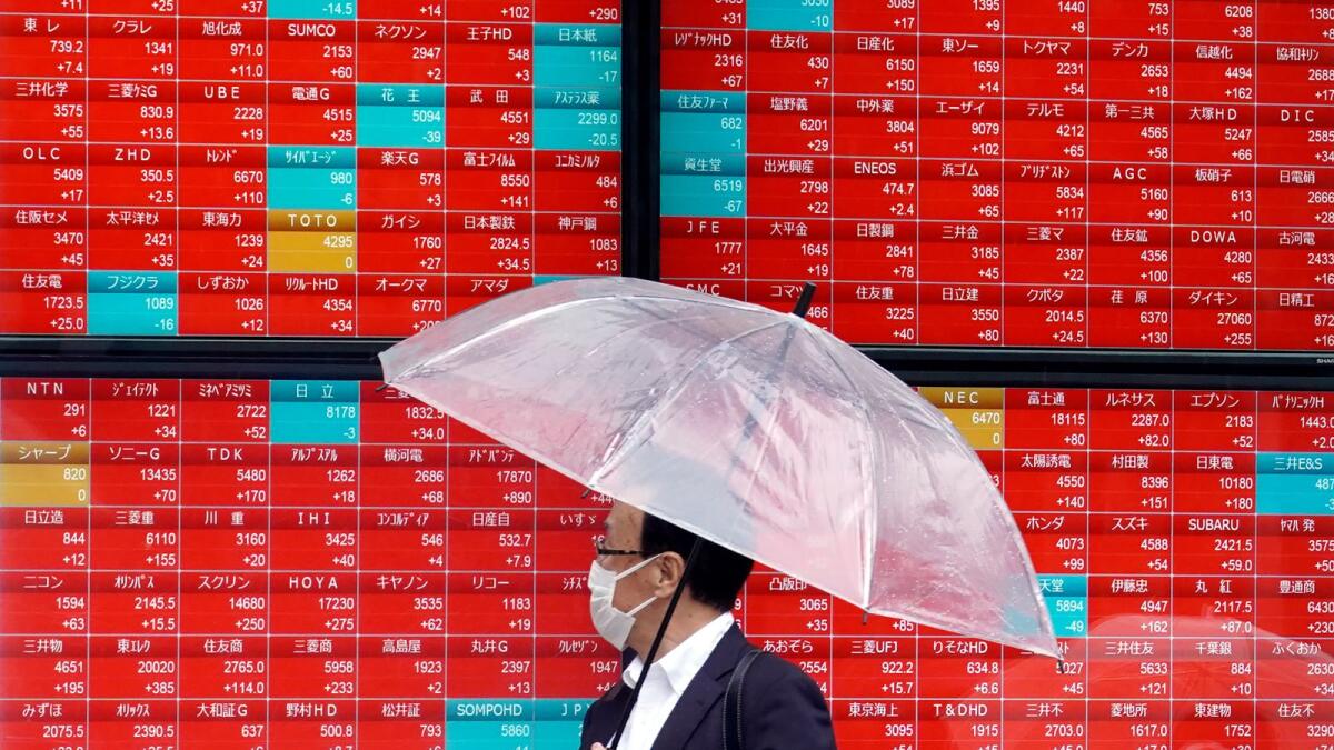 A person looks at an electronic stock board showing Japan's Nikkei 225 index at a securities firm in the rain on Monday in Tokyo. Asian shares are mostly higher after President Joe Biden and House Speaker Kevin McCarthy reached a final agreement on a deal to raise the U.S. national debt ceiling. — AP