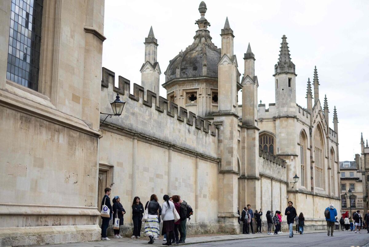 Tour guides Devika and Oliver talk with a group of people attending an 'Uncomfortable Oxford' tour outside the College of All Souls, in Oxford, on October 20, 2023. — AFP