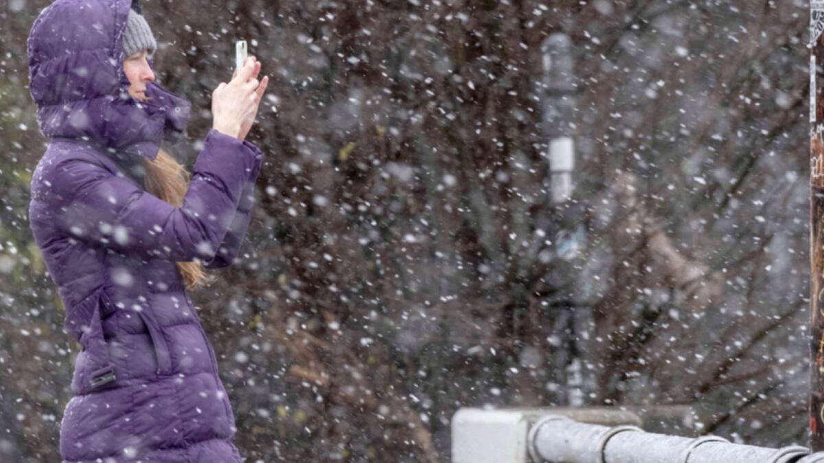 Bridget Step stops for a photo of the snow while watching the snow fall in Atlanta as a winter storm rolls into the area. — AP