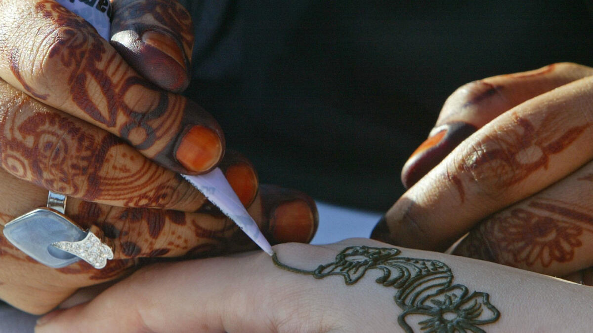 A United Arab Emirates woman paints henna on a Lebanese woman's hand during a tourist festival held in downtown Beirut May 20, 2005. The UAE tourist festival is held in Beirut to encourage tourists to travel between the two countries. REUTERS