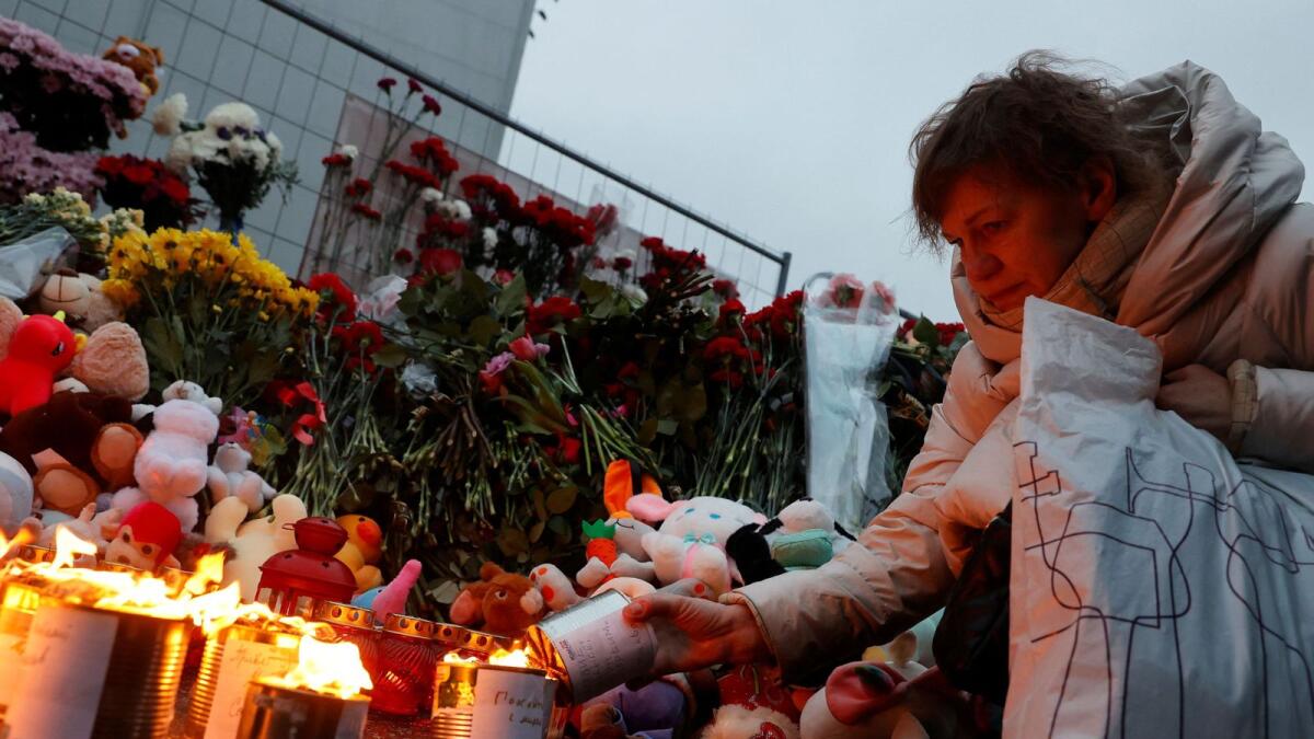 A woman lights a candle at a makeshift memorial to the victims of a shooting attack at the Crocus City Hall concert venue in the Moscow Region. — Reuters