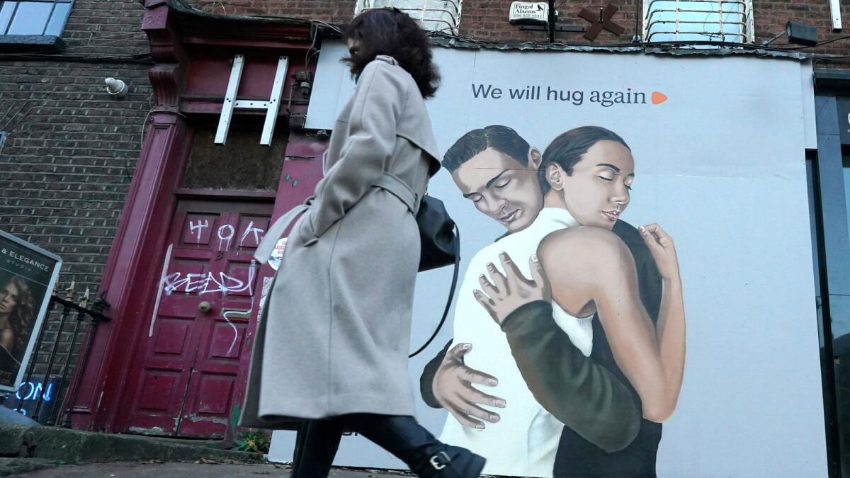 A woman walks past a poster saying 'we will hug again' amid the coronavirus disease (COVID-19) outbreak in Dublin, Ireland, November 22, 2020.