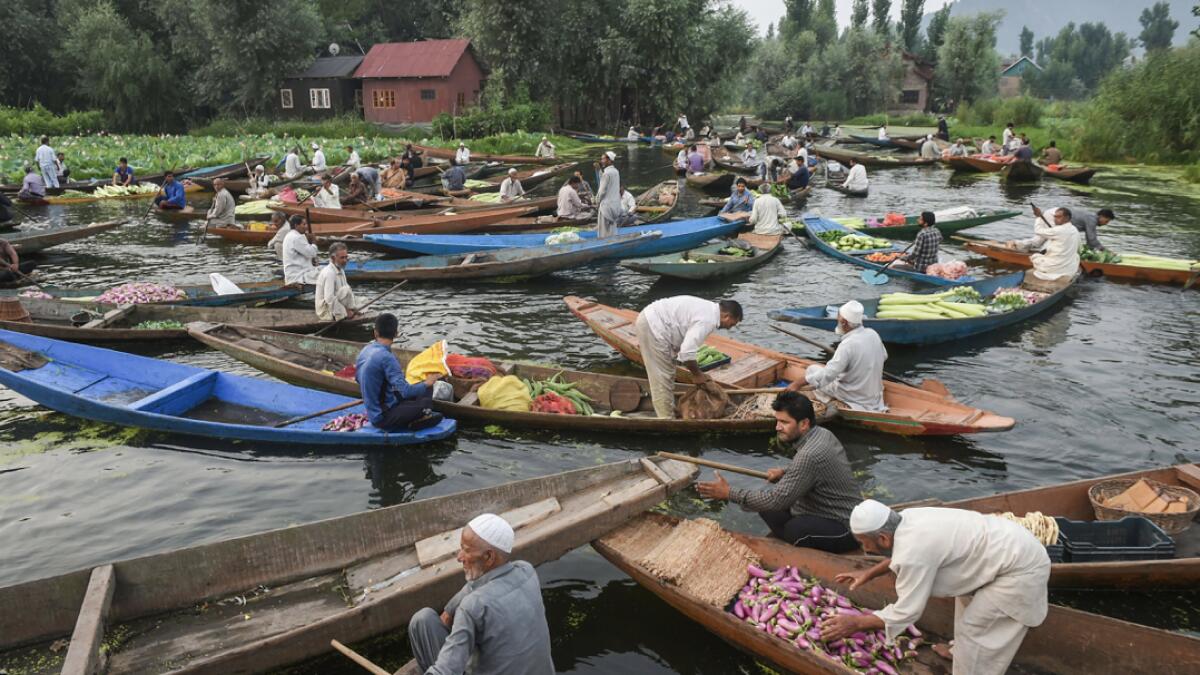 Farmers and traders wait for customers to sell their produce during daybreak at a floating market on the Dal Lake, in Srinagar.  Vegetables traded in this floating market are supplied to Srinagar and few parts of the Kashmir valley. It is one of the major sources of income for the lake dwellers. Photo: PTI