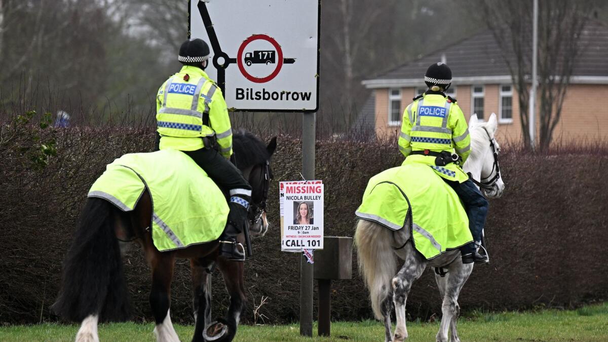 Mounted police officers ride their horses past a post appealing for information on missing Nicola 'Nikki' Bulley in St Michael's on Wyre, near Preston, north west England, following the discovery of a body in the River Wyre on Sunday.  — AFP
