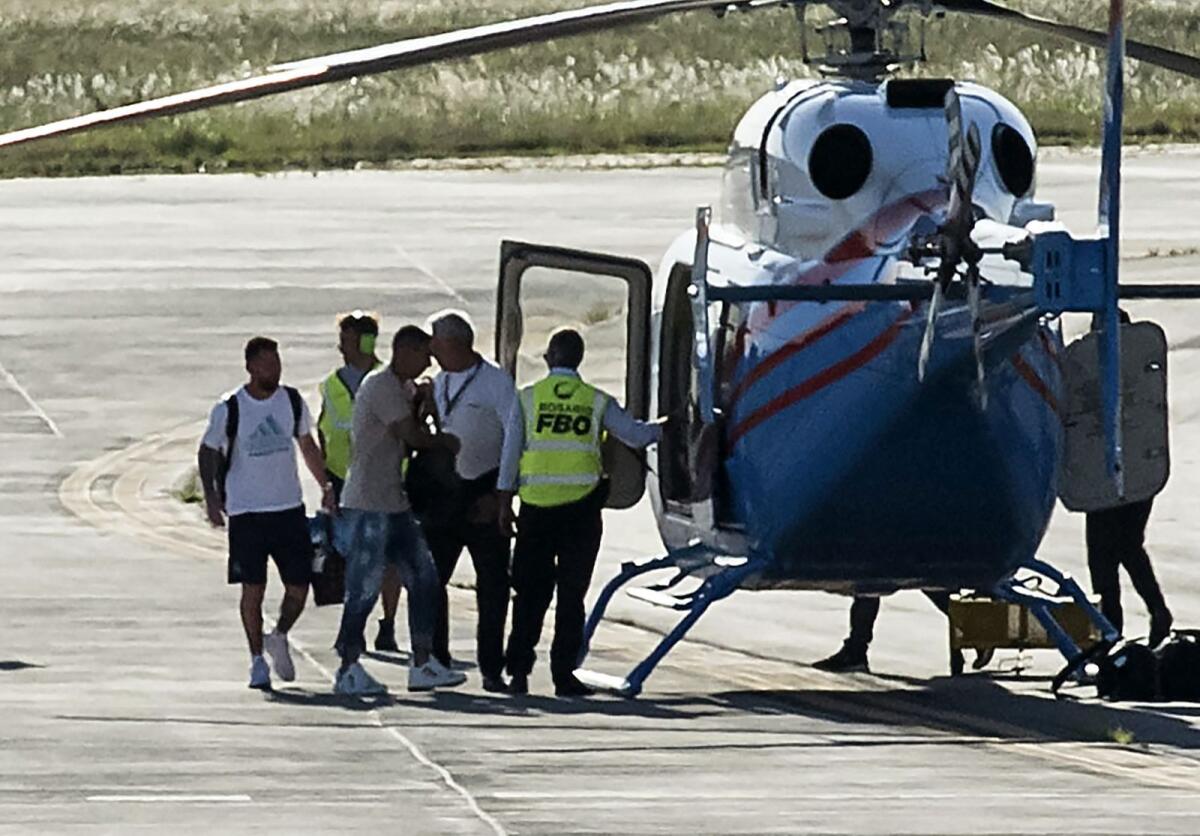 Argentina's Lionel Messi (L) and Argentina's Angel Di Maria (C) prepare to board a helicopter heading to their respective homes, on arrival at the Islas Malvinas international airport in Rosario, Santa Fe province, Argentina, on December 20, 2022.  (Photo: AFP)