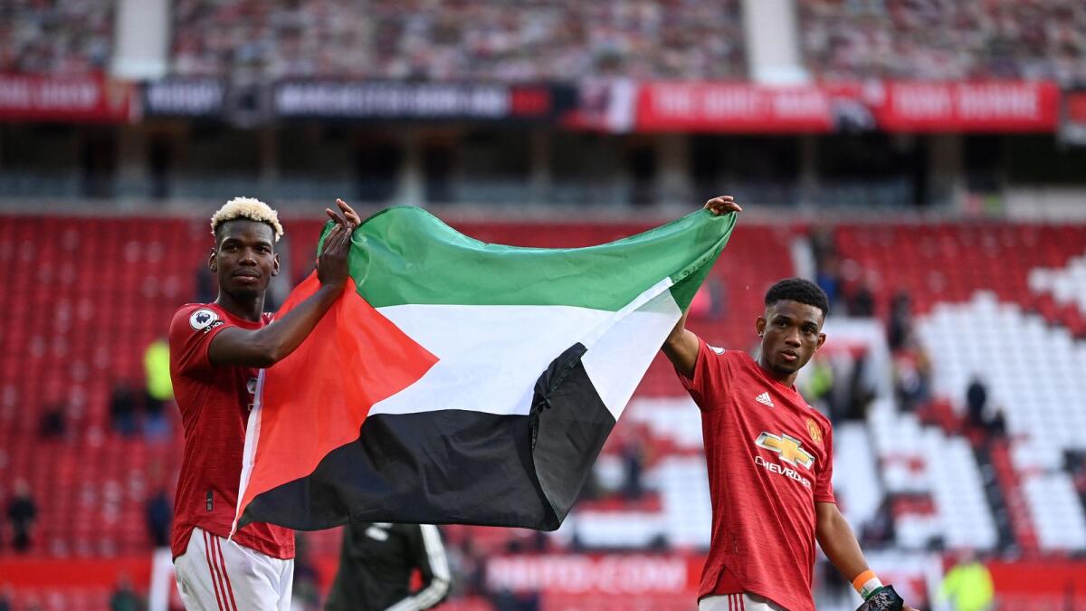Manchester United's Paul Pogba (left) and Amad Diallo hold up the Palestine flag following Tuesday's 1-1 Premier League draw with Fulham. (AFP)