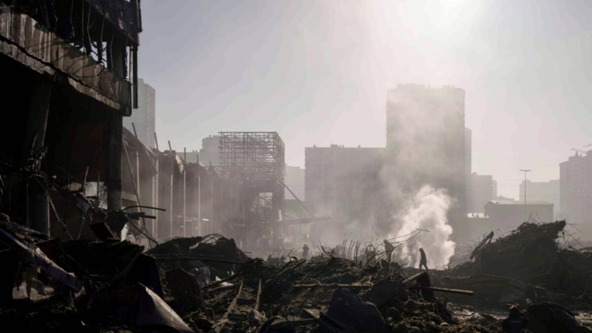 Firefighters extinguish a fire near a shopping center after shelling in Kyiv. — AP