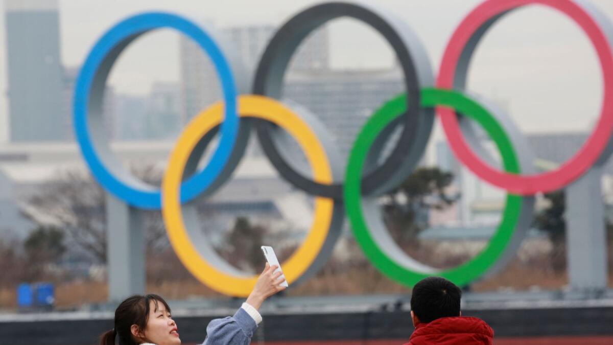 A woman poses for a selfie in front of the Olympic rings at Odaiba waterfront in Tokyo.  (AP)