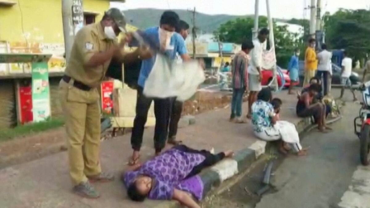People fan a woman lying on a roadside following a gas leak at the LG Polymers Plant Building in Visakhapatnam, Andhra Pradesh, India, May 7, 2020, in this still image taken from video.