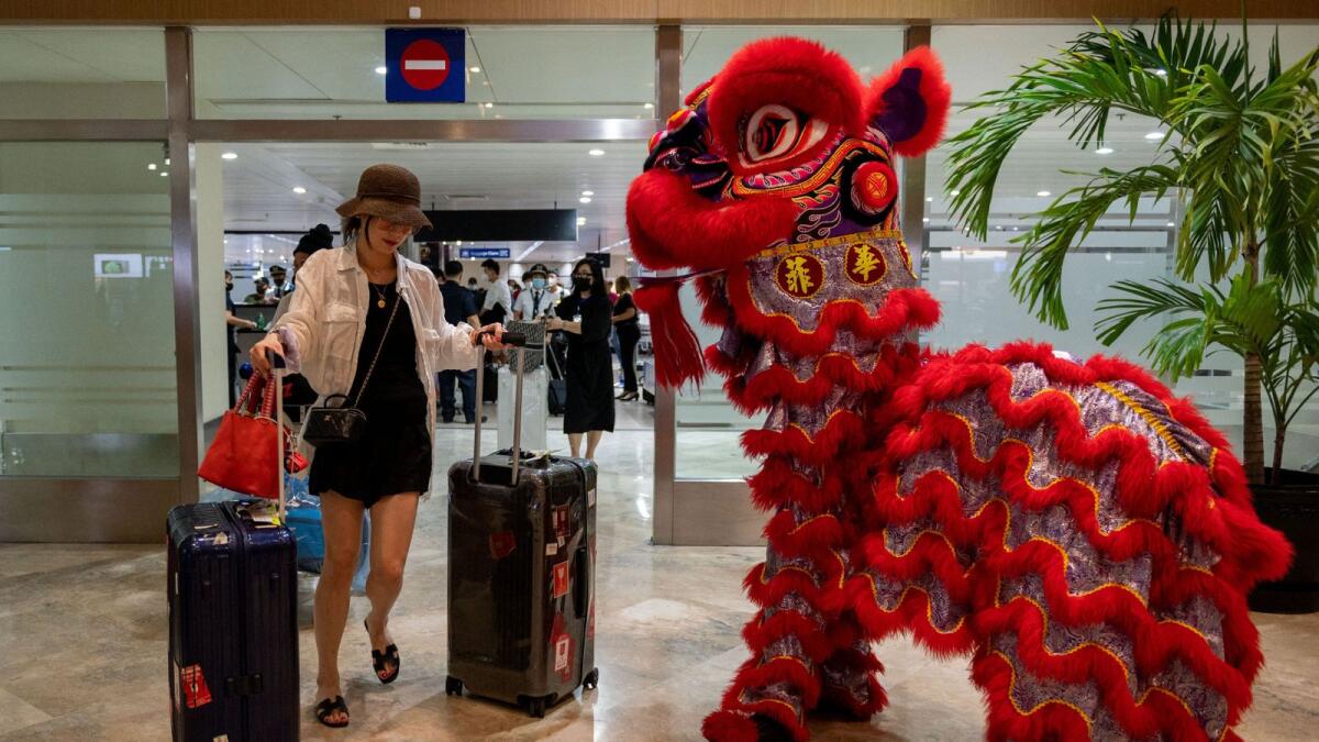 A dragon dance performer greets a traveler from China at the Ninoy Aquino International Airport in Pasay City, Metro Manila, the Philippines, on Tuesday. — Reuters