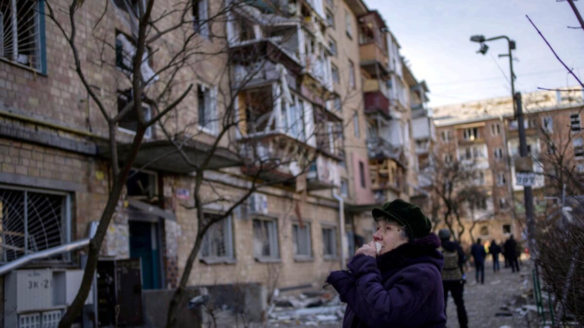 A woman looks at residential buildings damaged by a bomb in Kyiv. — AP